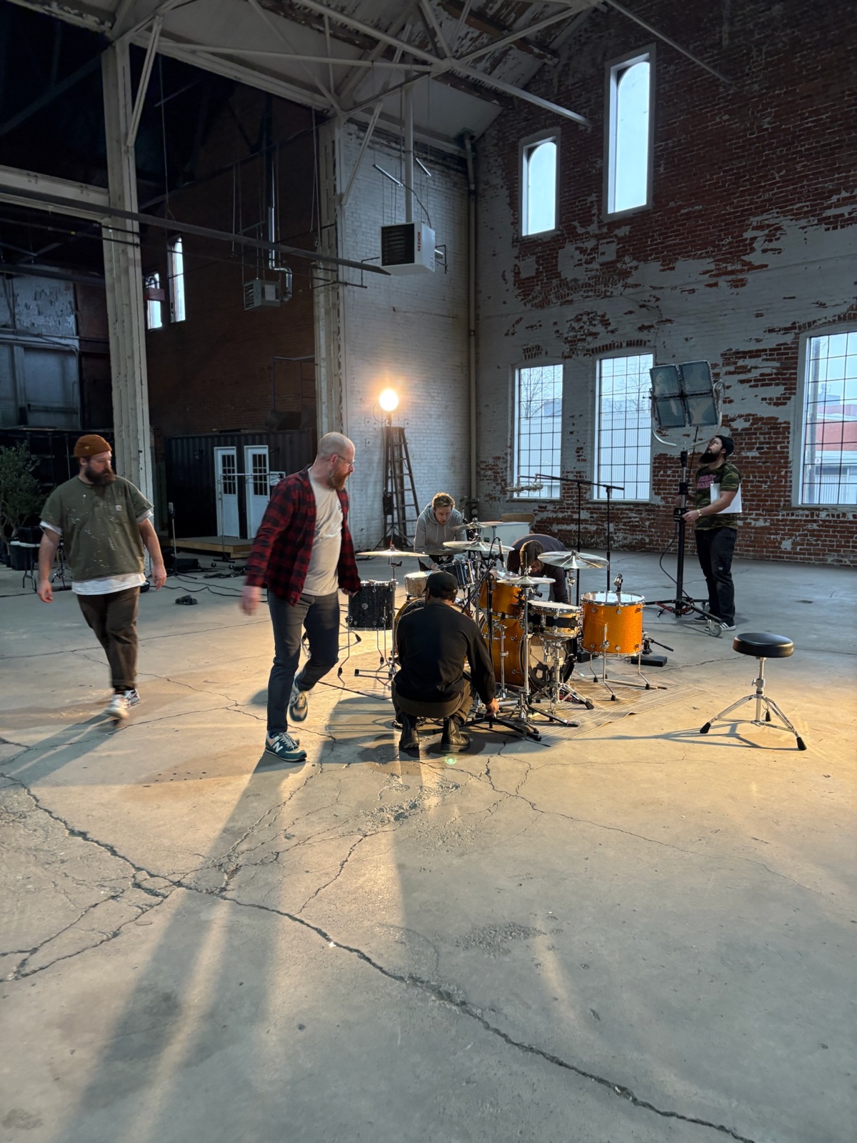 The small crew setting up the kit in the sunlit brick studio