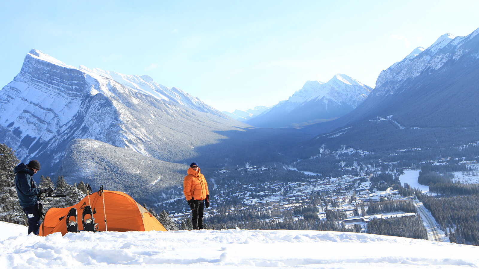 The winter camping location - a tent pitched on a snowy ridge above a mountain valley