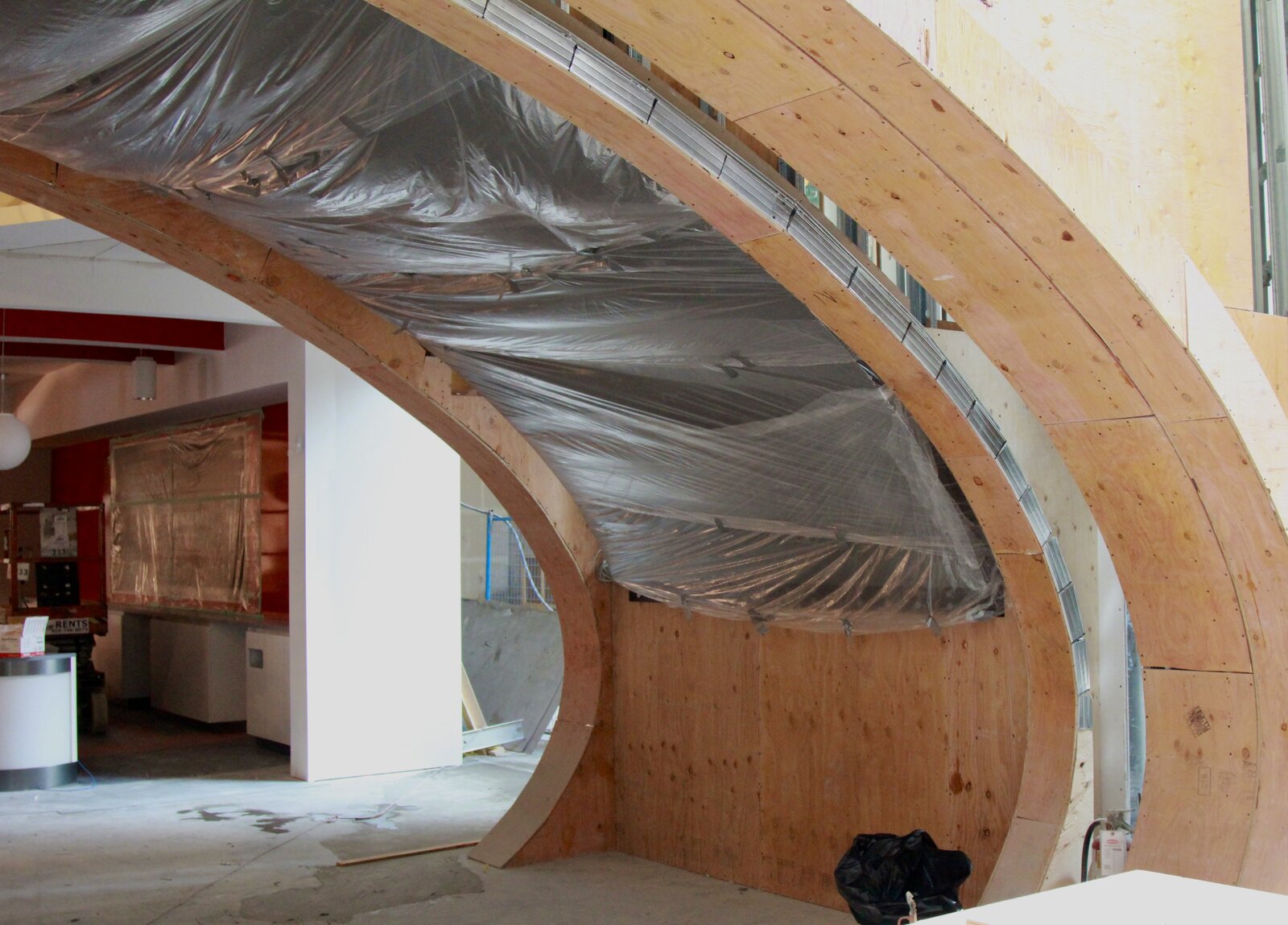 The curve of the portal framed out in plywood, seen from inside the unfinished store