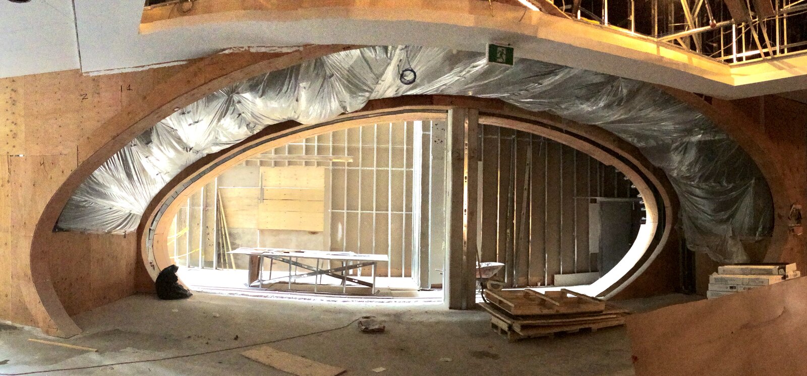 The entrance portal under construction - the elliptical opening framed in plywood, the ceiling behind it wrapped in plastic sheeting