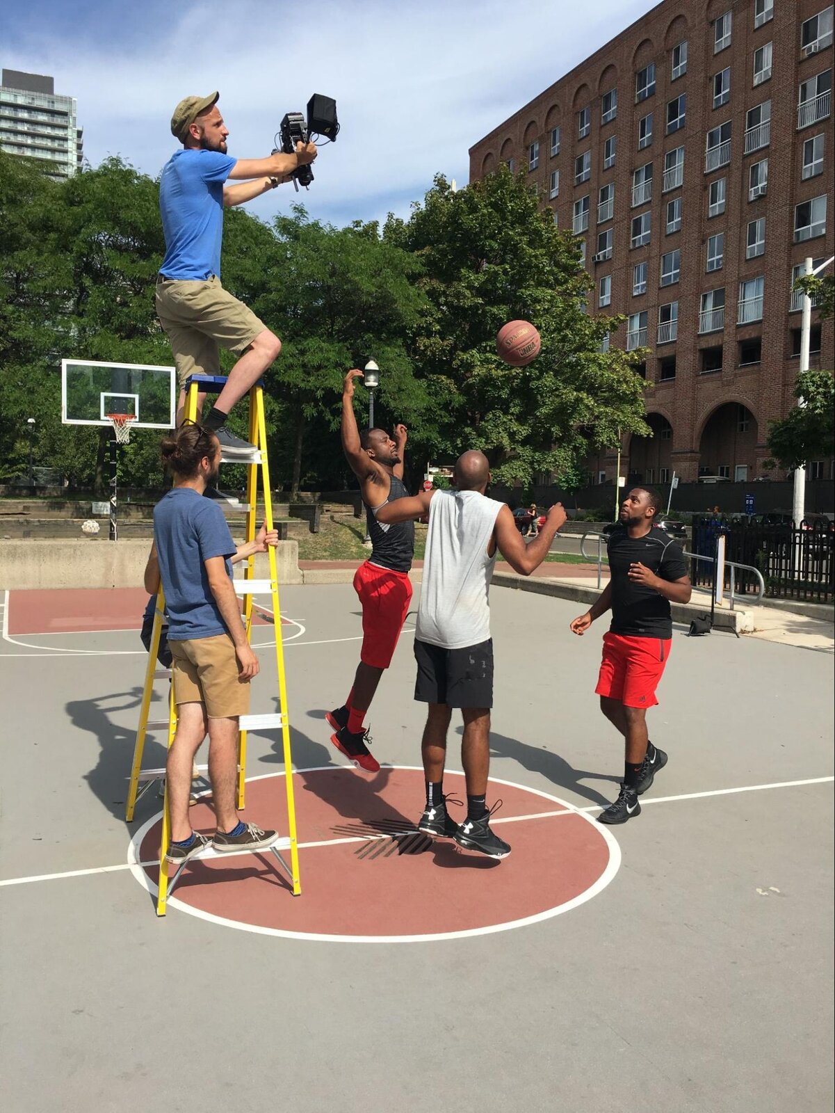 Shooting the basketball play from a stepladder above the court